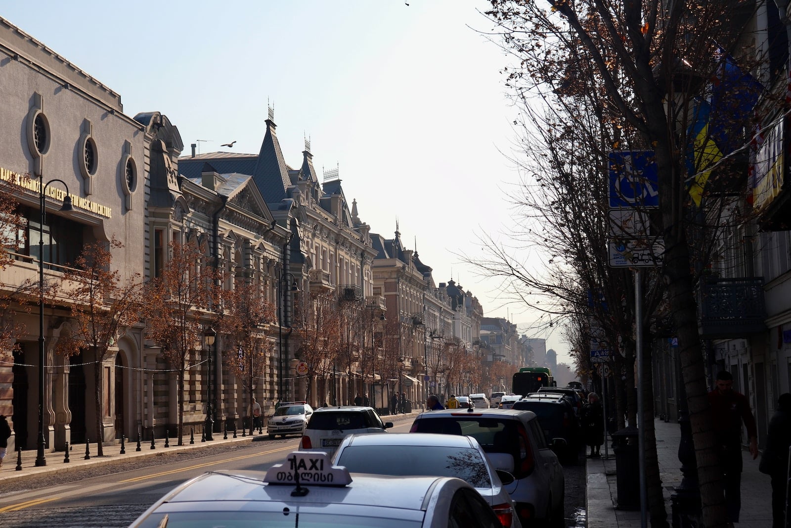 a row of buildings on a street with cars parked on the side of the street